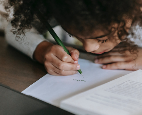 Photo of little Black girl reading and writing.